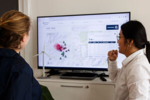 Two women looking at a monitor screen displaying LASSIE Lightning Surveillance dashboard